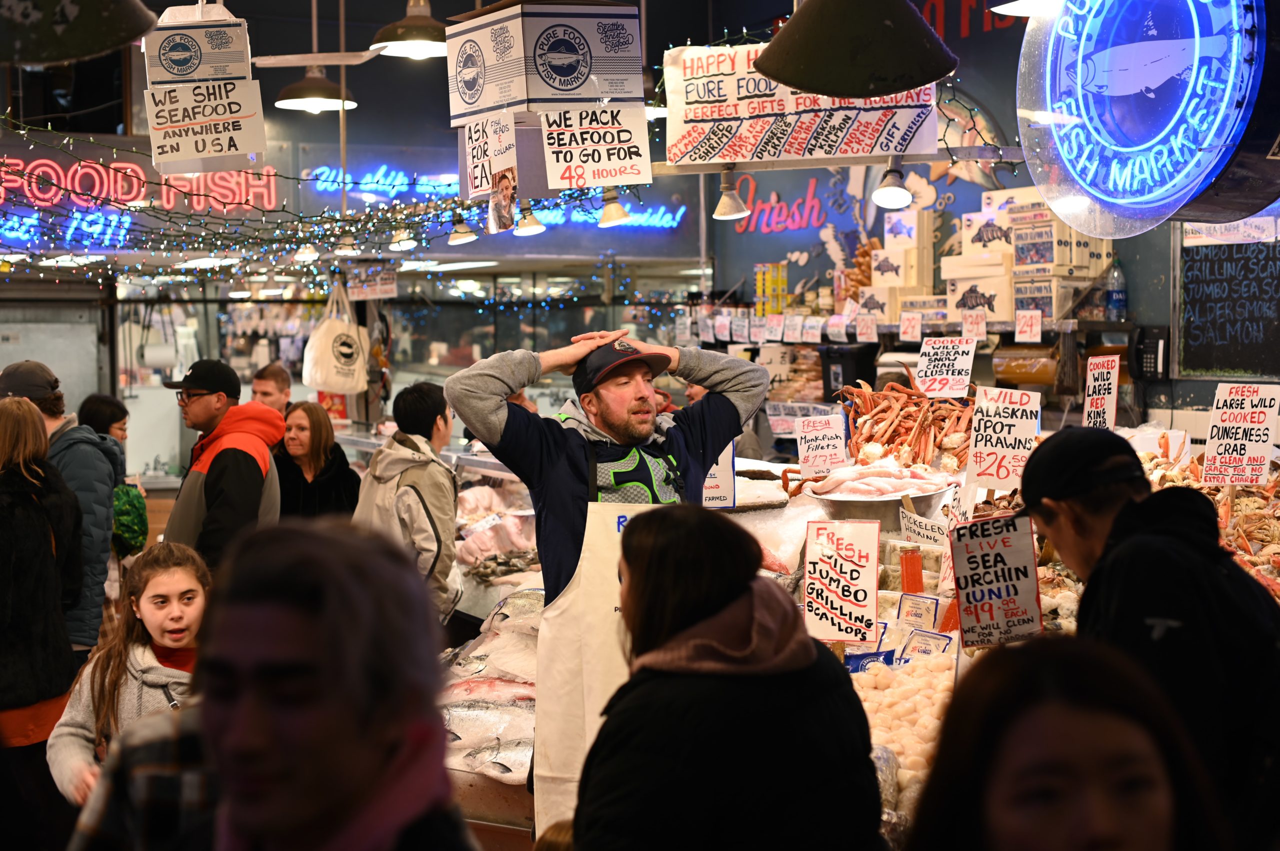 Vendor standing in Pike's Place Market in Seattle, Washington amongst crowd of people. 